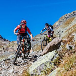 two women riding a mountain bike downhill on the stones on the mountain