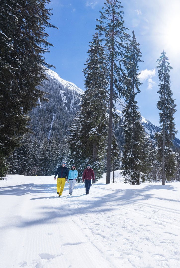 Drei Leute laufen im Schnee, mit einem Berg hinter in Davos