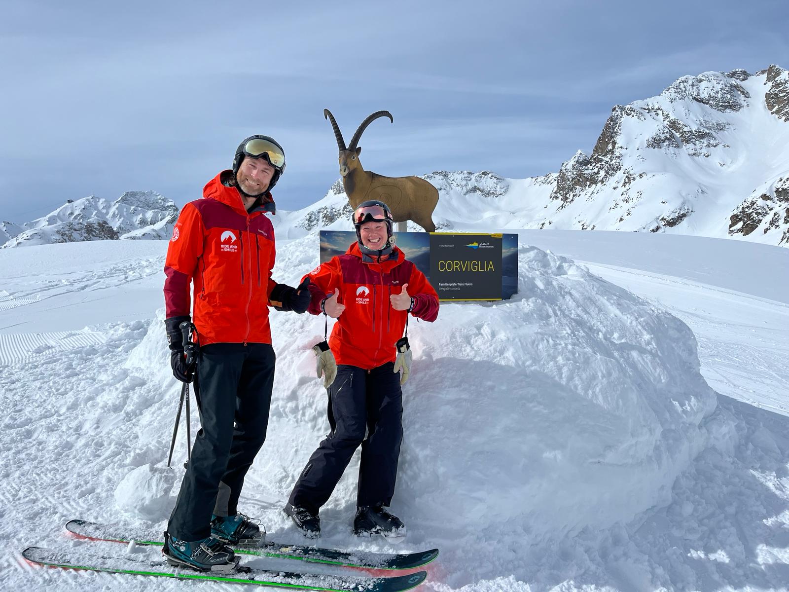 Two ski instructors in St. Moritz with an ibex in the background.