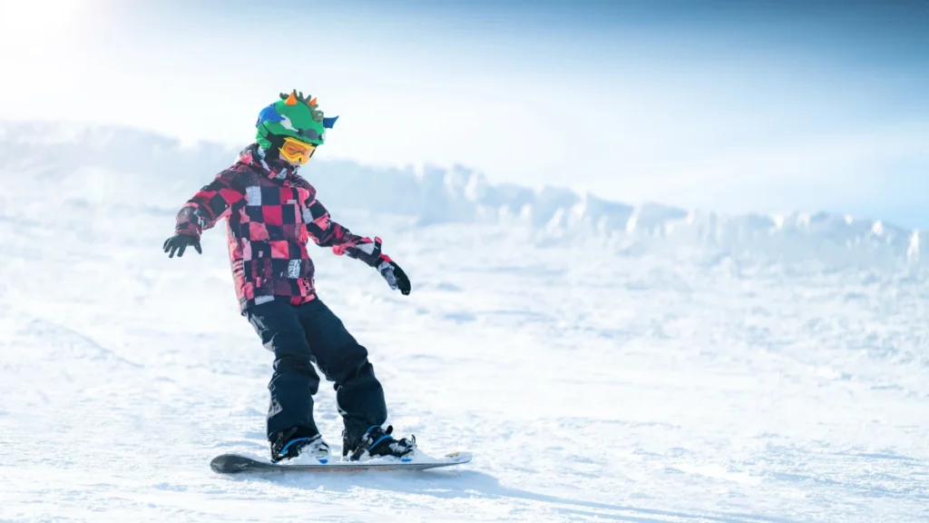 Private snowboard lesson for one child in Davos. The child is wearing a green helmet and black pants.