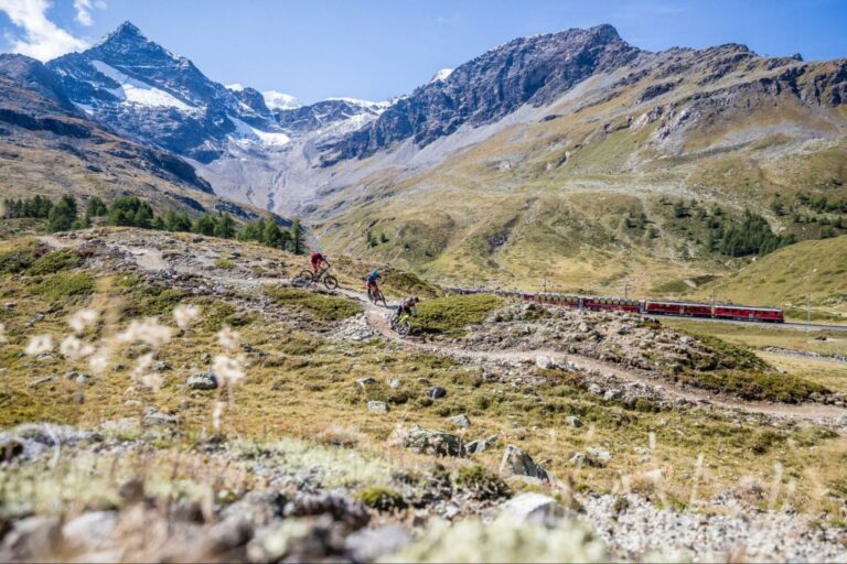 Mountain bikers riding in the mountains near a train.