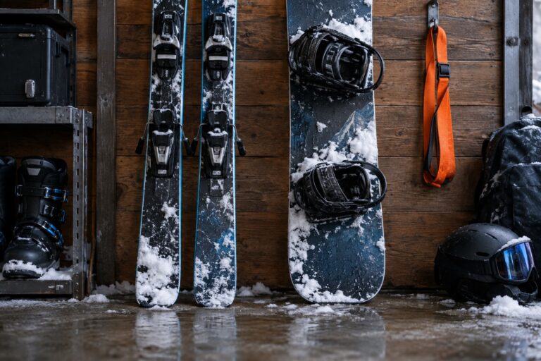 Ein Paar Ski und ein Snowboard lehnen nebeneinander an einer Holzwand